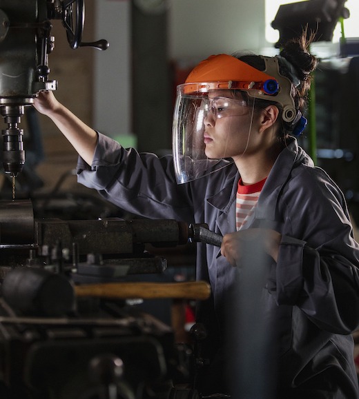 Woman working in a manufacturing facility using heavy machinery