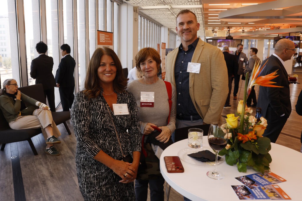Three people at a networking event smiling together