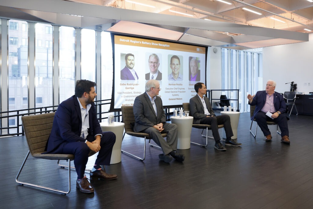 A panel of speakers sitting down and talking on a stage