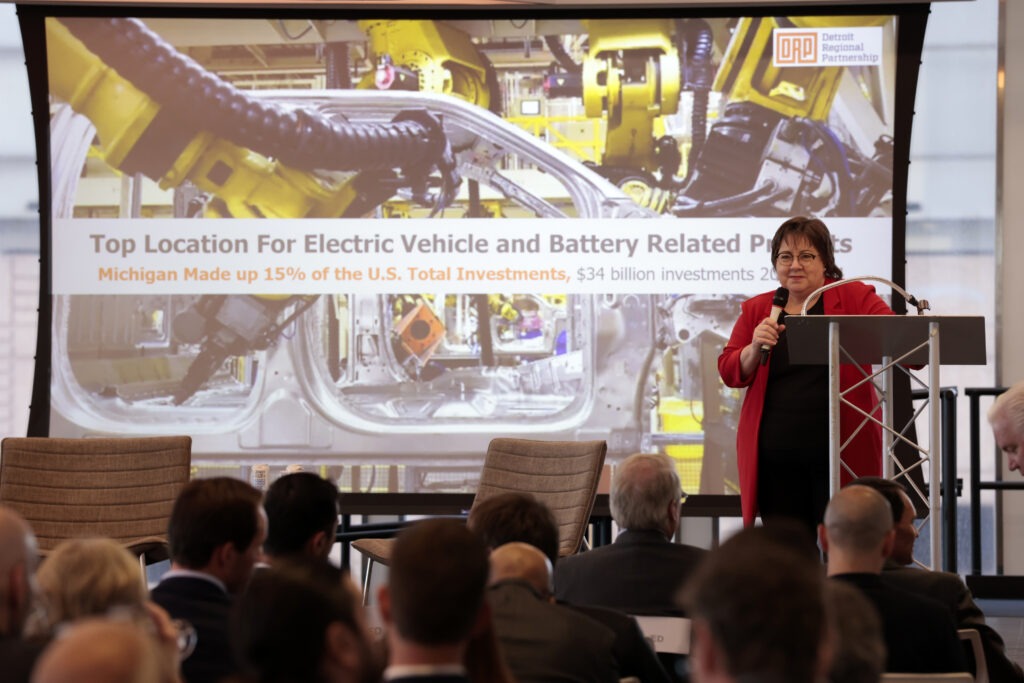 A woman wearing a red cardigan holding a microphone on a stage