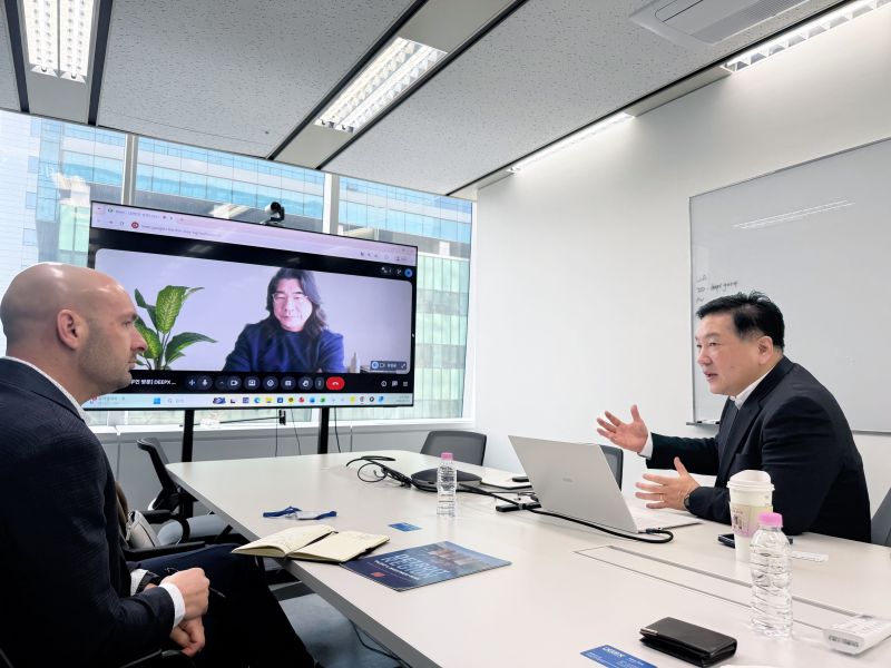 Two people talking across a table with someone on a virtual call